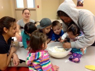 Teenage parents engage their toddlers in some kitchen fun.
