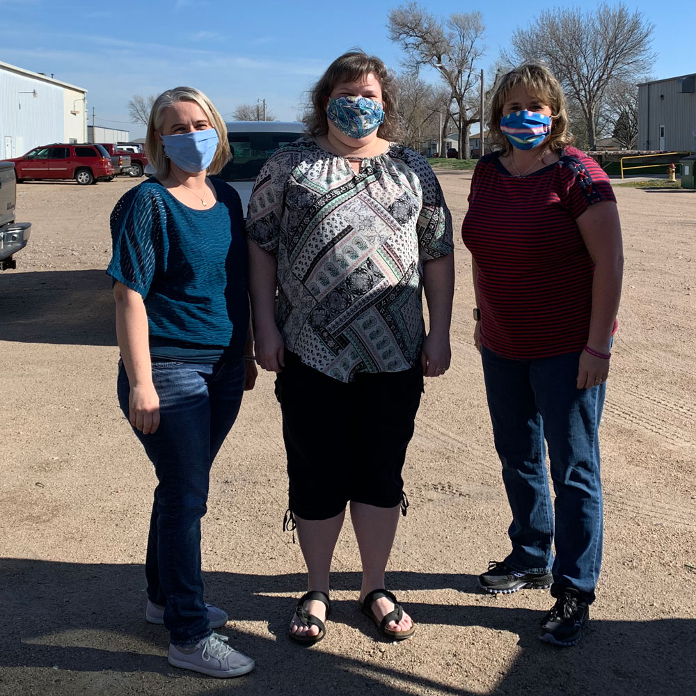 Sanitizer donation pick-up and non-box holding photo of three Hall County Community Collaborative (H3C) coordinators of the birth to 11 programs. From left to right: Saffron Buettner with Communities for Kids, April Sundberg with Rooted in Relationships/Sixpence, and H3C with Julie Nash.
