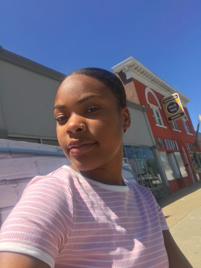 Tested and true courage: A'zja stands outside the bus stop where, as a preteen, she taught herself how to take public transportation. 